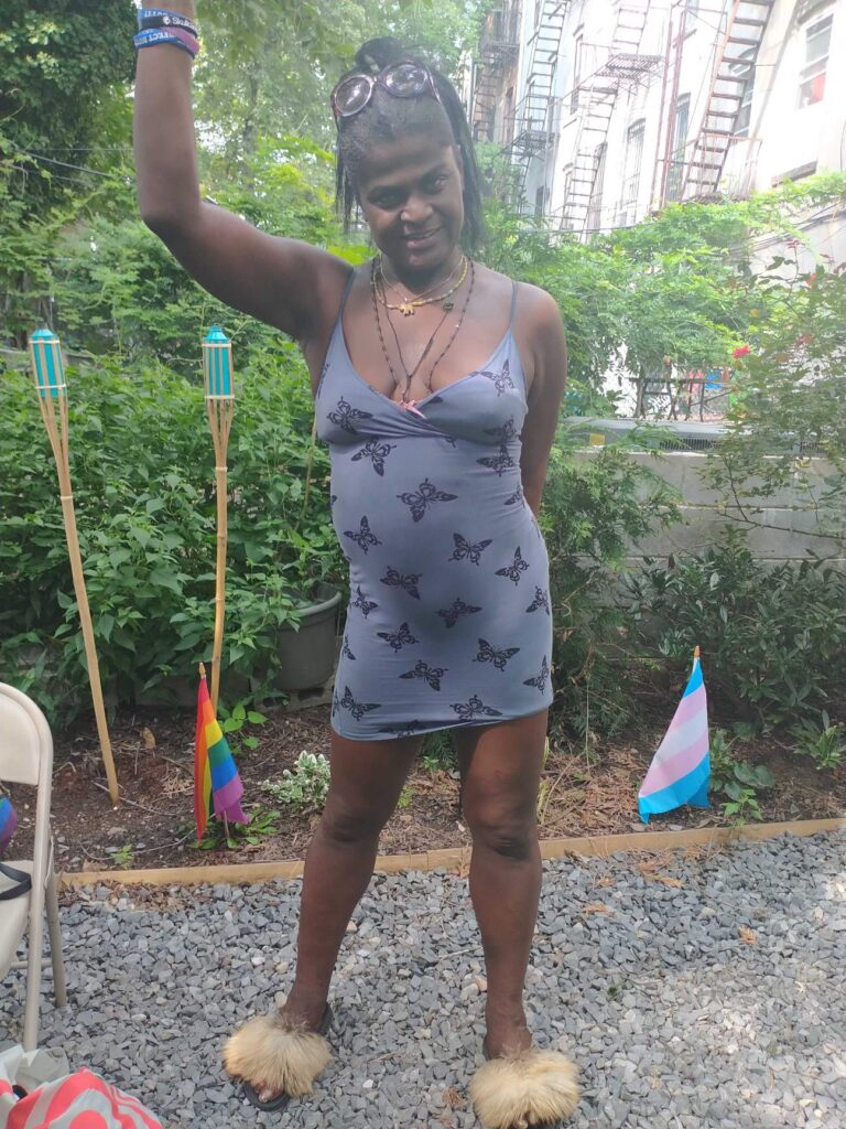 Person Posing in Front of an LGBTQ+ and Trans Flag